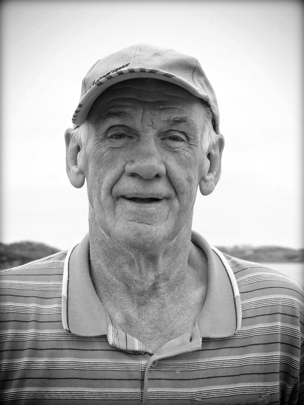portrait d’un homme âgé, il porte un casquette, il me regarde et il sourit