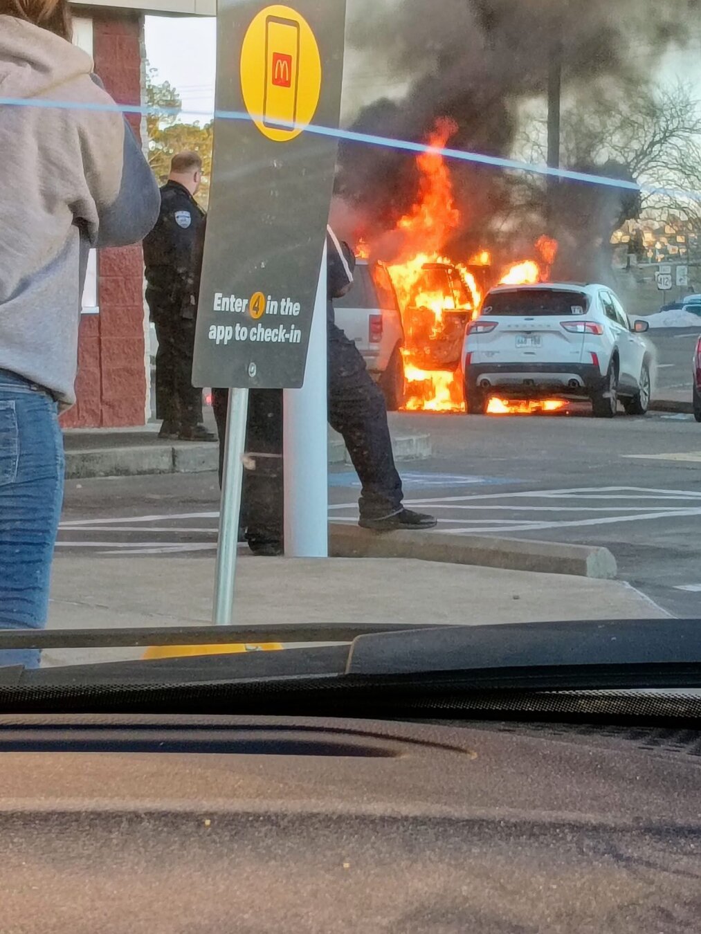 Police watch as a vehicle burns jn a McDonalds parking lot.