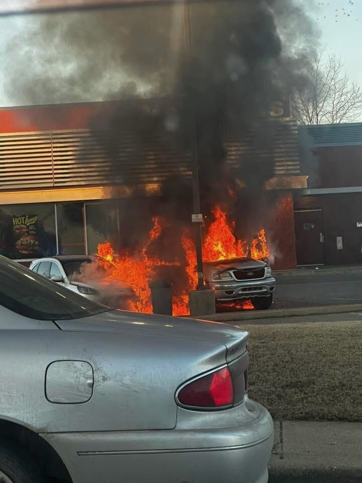 Front view of the vehicle showing McDonalds behind it as it’s on fire.