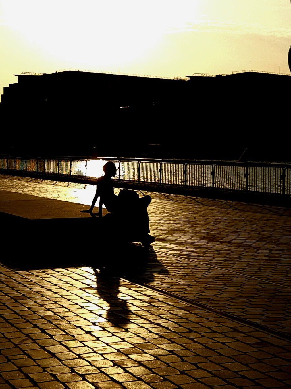 Photo d'un homme assis sur un banc en contre-jour dans une lumière jaune dorée