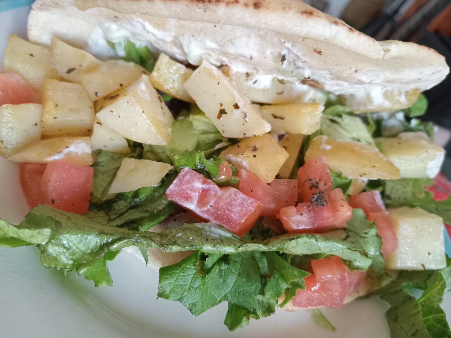 beef gyro with potatoes, lettuce, and tomatoes with tzatziki sauce