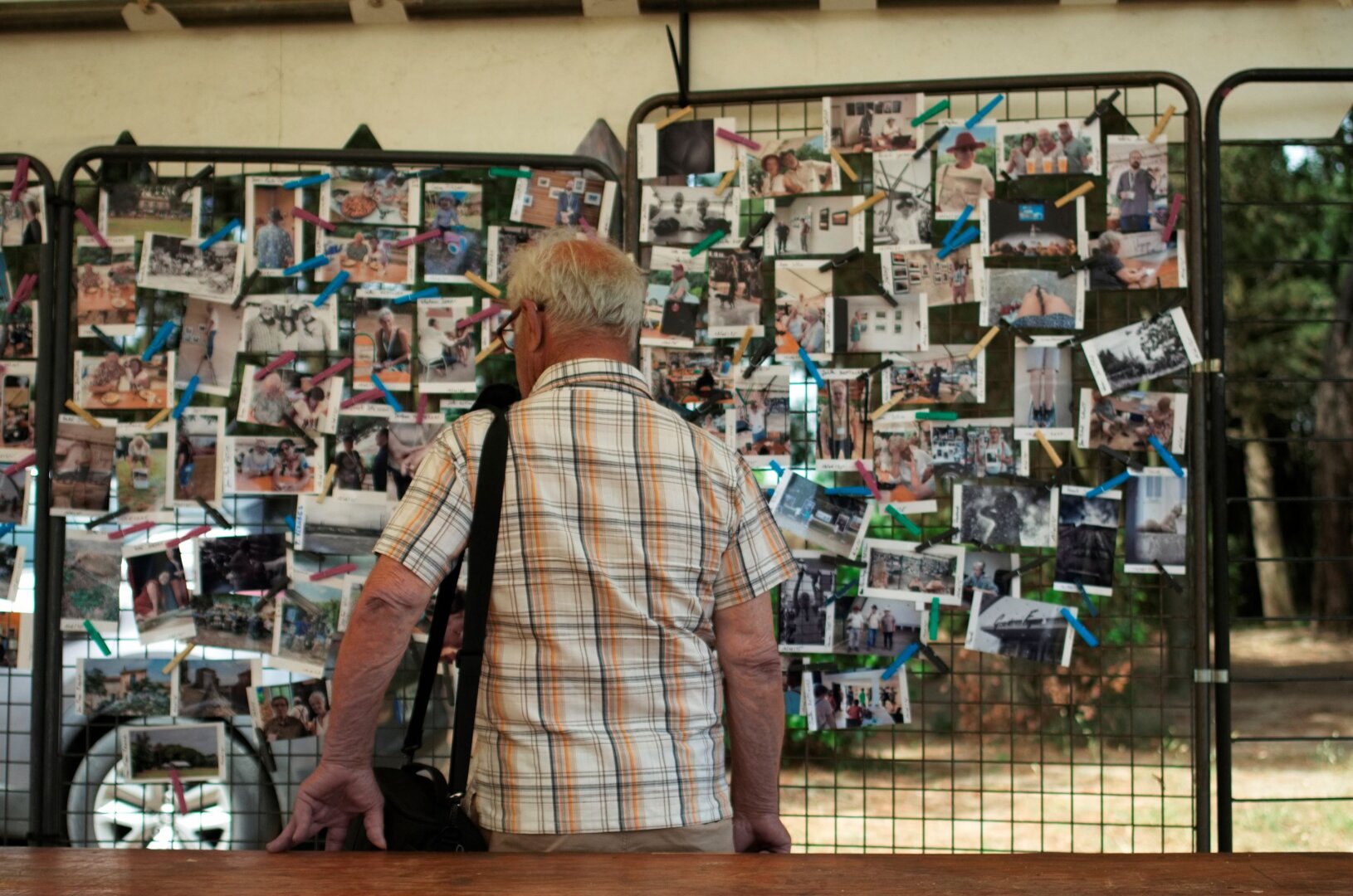 Photo couleur d'un photographe regardant des photos épinglées sur une grille d'exposition