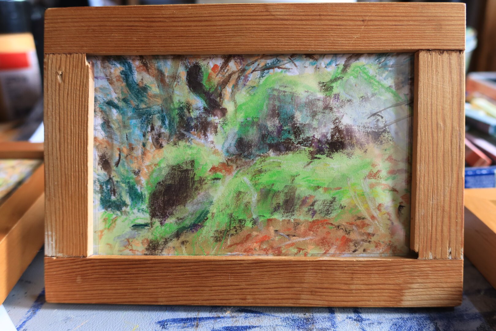 petit tableau horizontal de sous-bois dans un cadre en bois fait à l'aquarelle et au pastel, dans des tons verts et orange