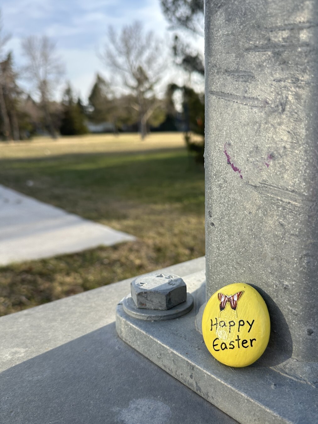 Painted rock with ‘Happy Easter!’ message left aside a lamppost to be spotted by passersby.