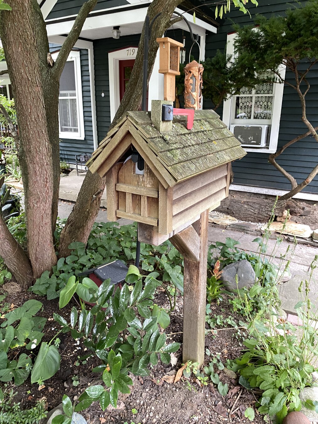 Mailbox designed like a wooden cabin, with a shingled roof and wooden slate siding.