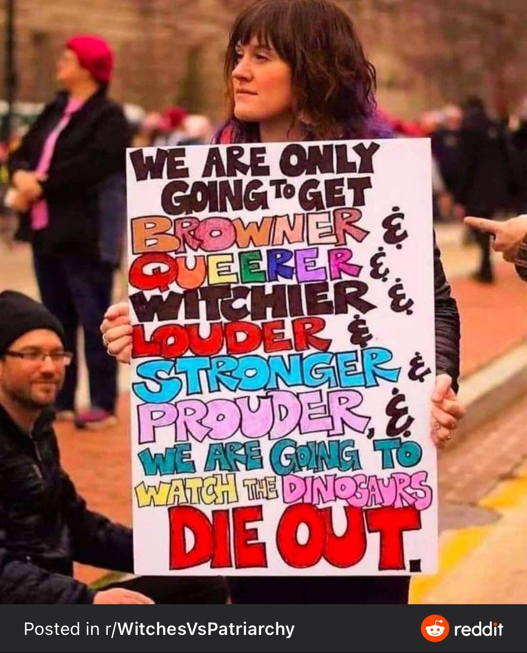 Meme with young person with brown skin holding a protest sign that says “We are only going to get browner & queerer & witchier & louder & stronger & prouder & we are going to watch the dinosaurs die out” in large, cheery, colorful lettering.