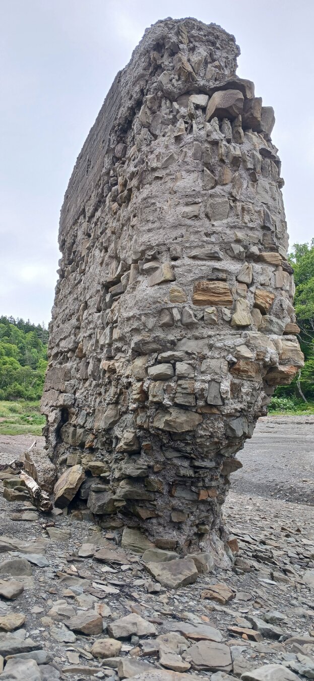 crumbling remnants of old train bridge support made up of concrete and local stones