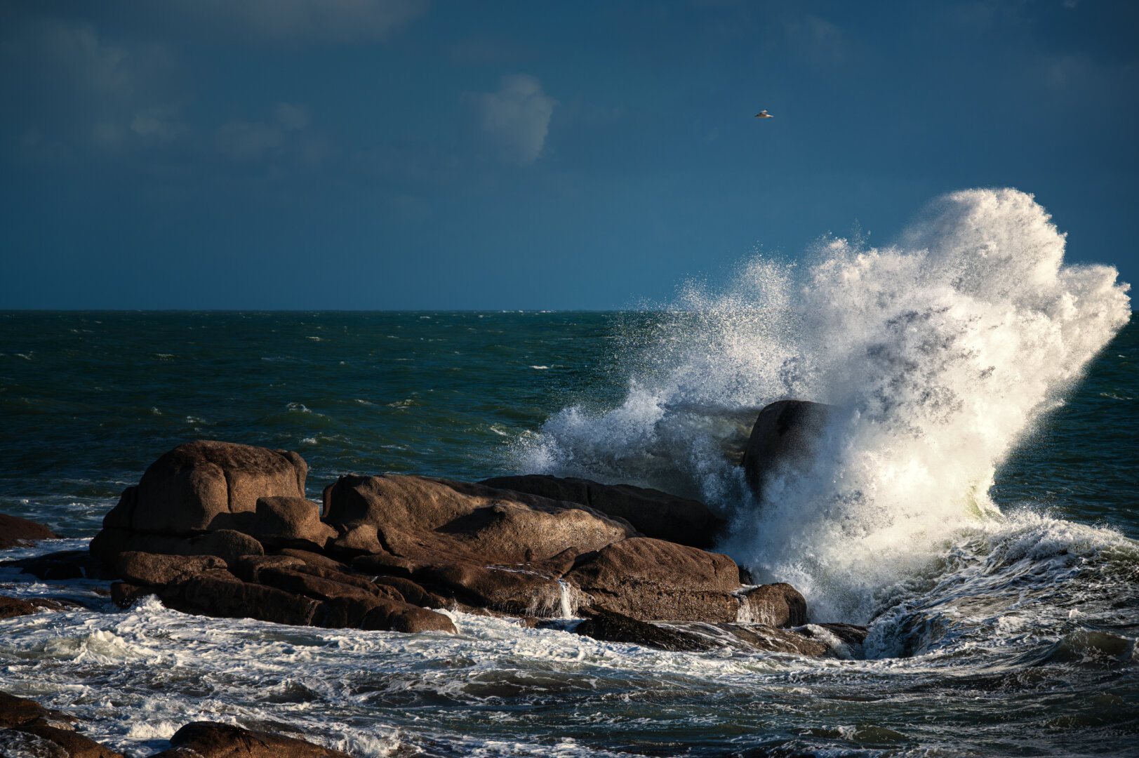 Eine grosse Welle, die sich an einem Fels an der Küste der Bretagne bricht und hoch aufspritzt. Eine grosse Welle, die sich an einem Fels an der Küste der Bretagne bricht und hoch aufspritzt.