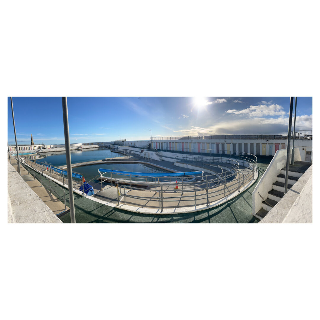 A panoramic image of a Penzance lido below a clear Bluesky