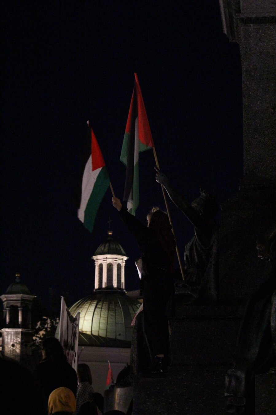 A girl and a statue wave the palestinian flags in the main square in Krakow