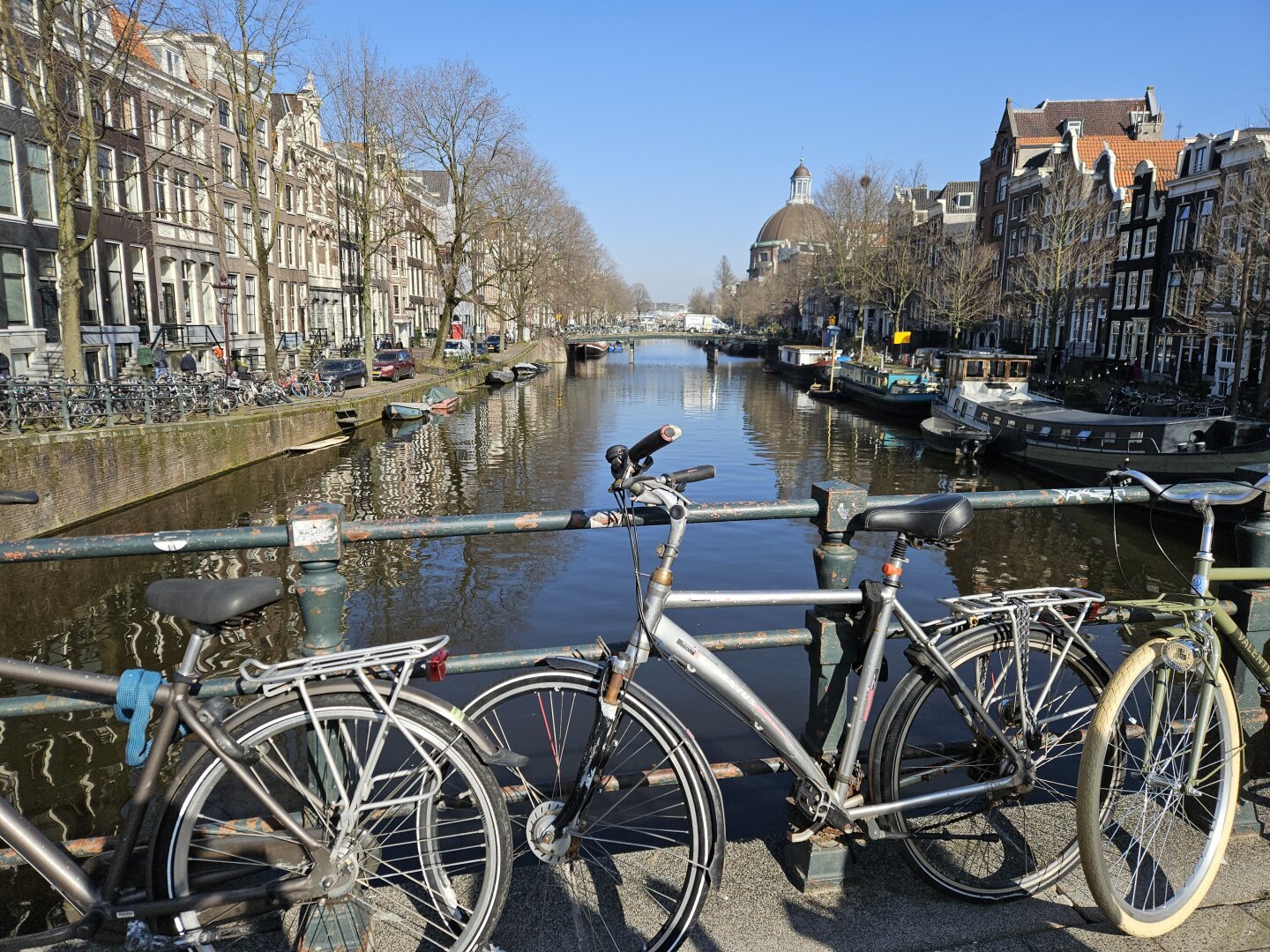 view of a canal in Amsterdam from a bridge with bikes in the foregeound