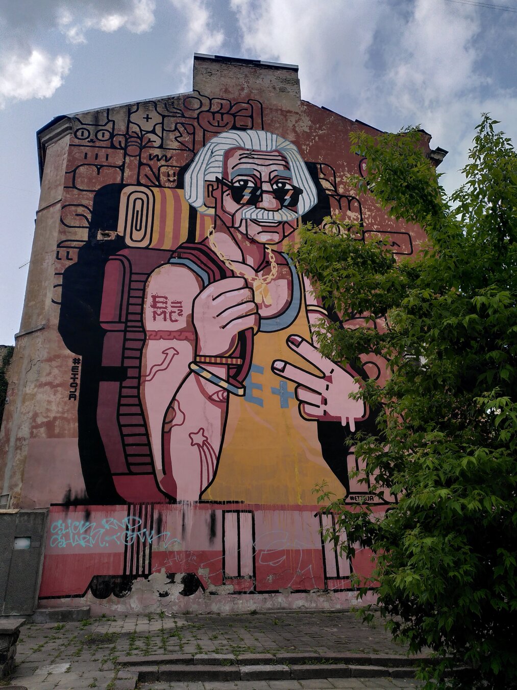 Albert Einstein as a backpacker: He wears a yellow shirt, sunglasses and a dark red backpack.
On his arm the famous formula E=MC2 is written.