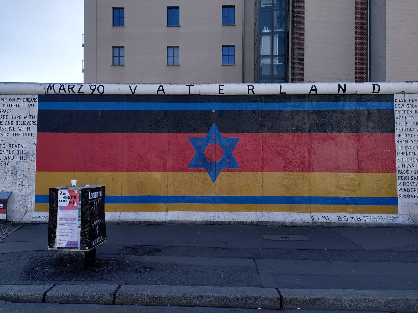 East Side Gallery - piece of art: You can see a fusion out of the German and the Israeli flag integrated into each other.