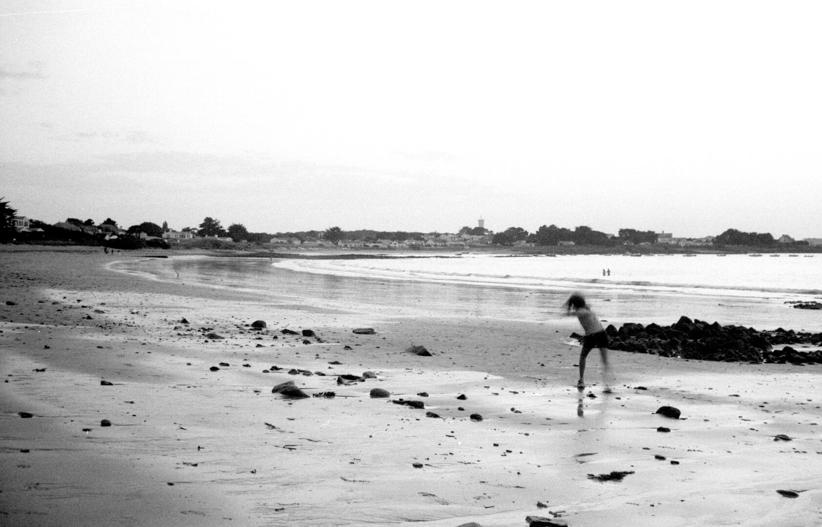 Kid playing on beach at dusk.