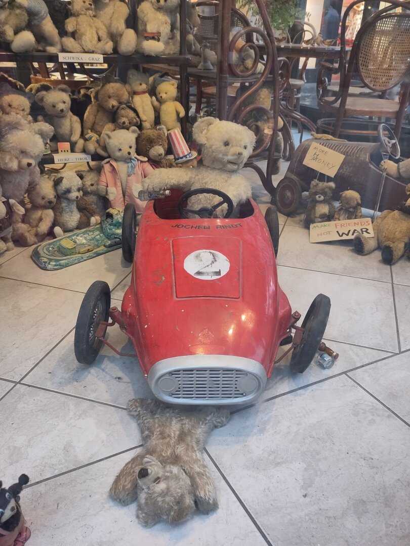A teddy bear in a red sportscar rode over another teddy bear.