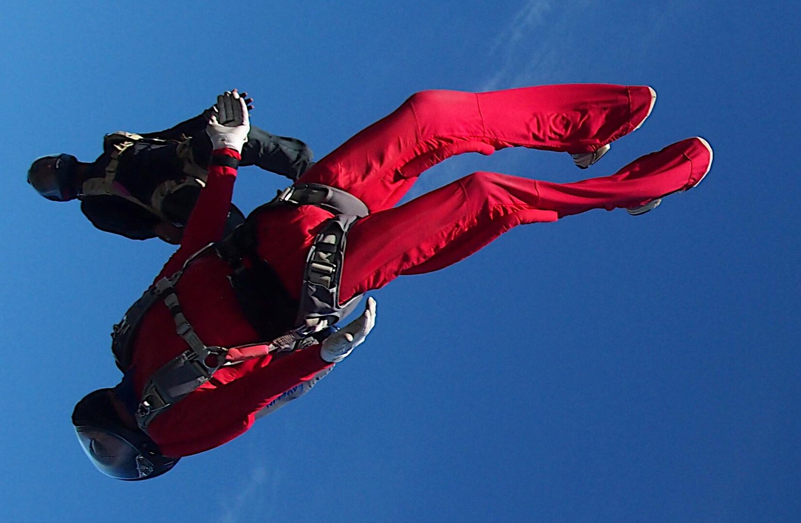 Two skydivers initiate their track to create distance from the formation before deployment.