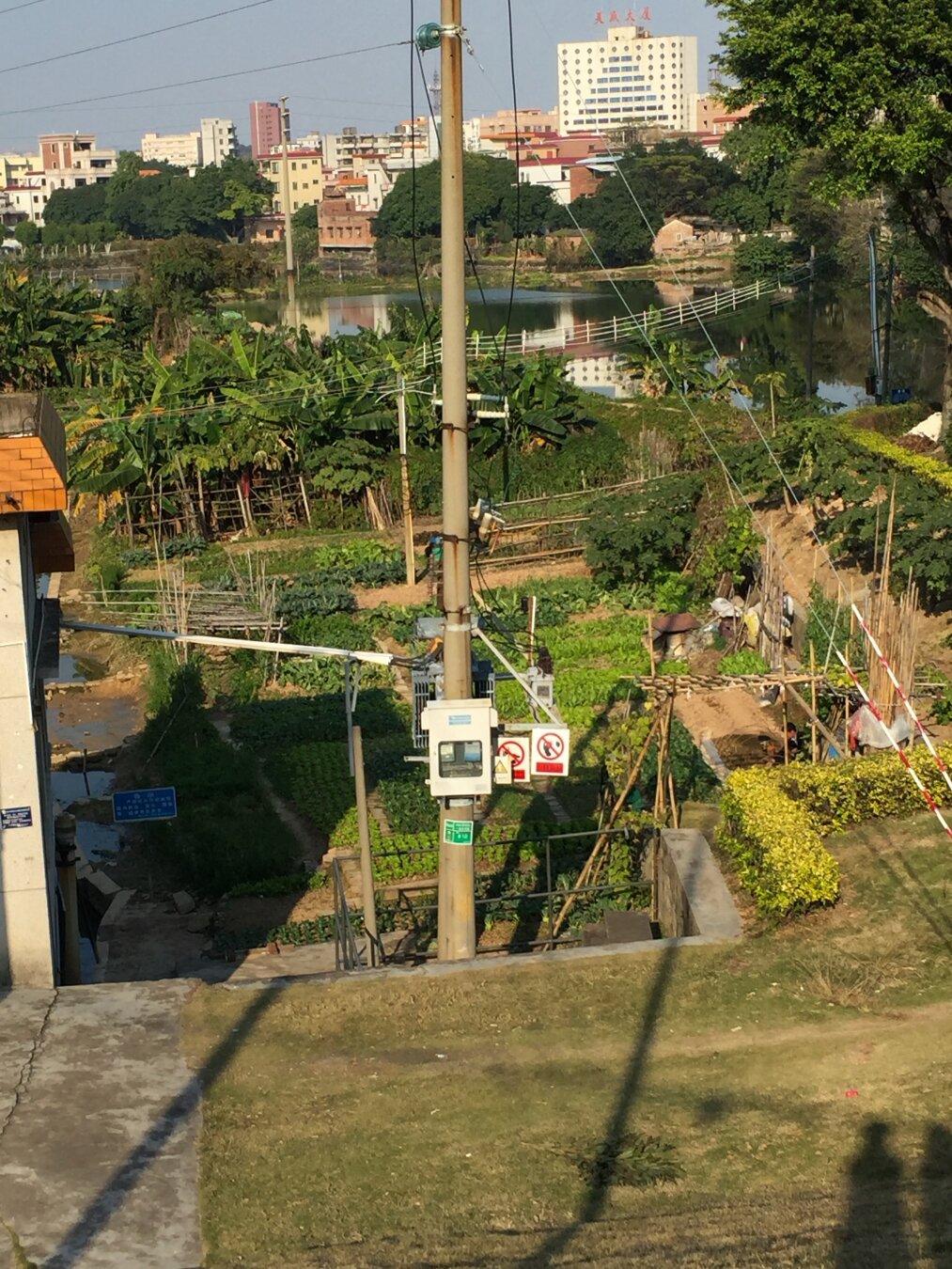 In the background the buildings in town are visible. In front of them is a small river. Closer to the camera are trees and then the garden next to someone’s house