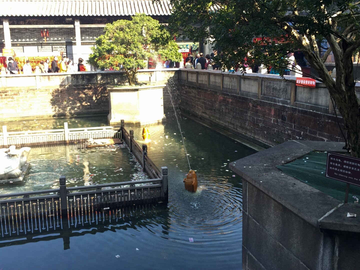 A courtyard in the Foshan Ancestral Temple. In the middle is a little pond. Raised above and around it is the main area with people walking around