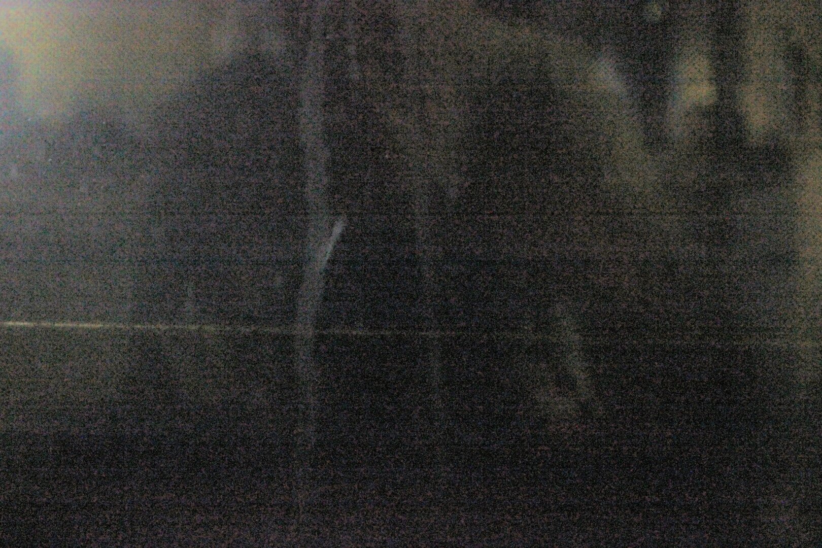 A dark scene. There is a horizontal line of metal leading back into darkness. A faint outline of a reflection
