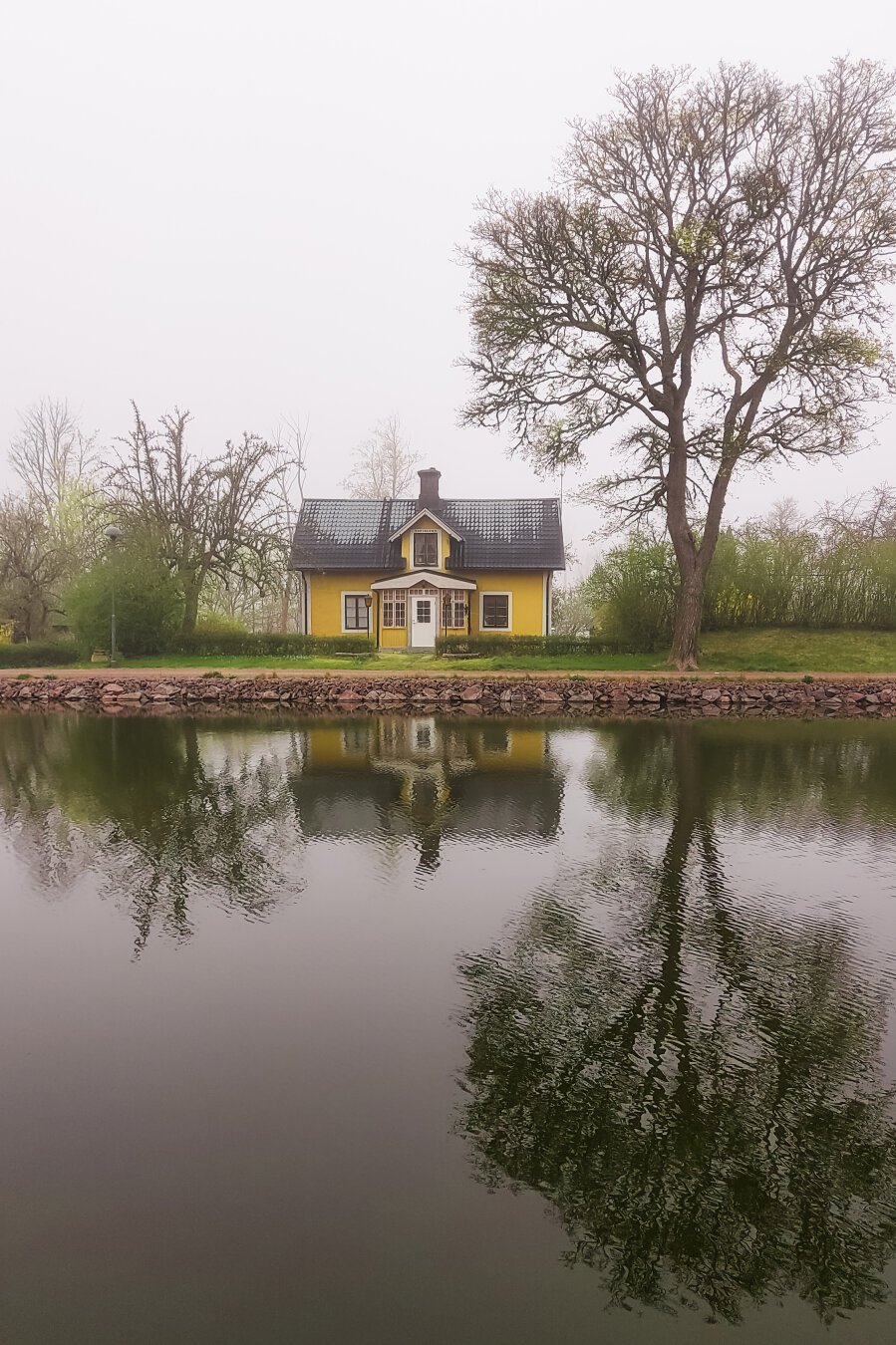 A yellow house with its reflection beautifully reflected on the calm waters of the canal.
