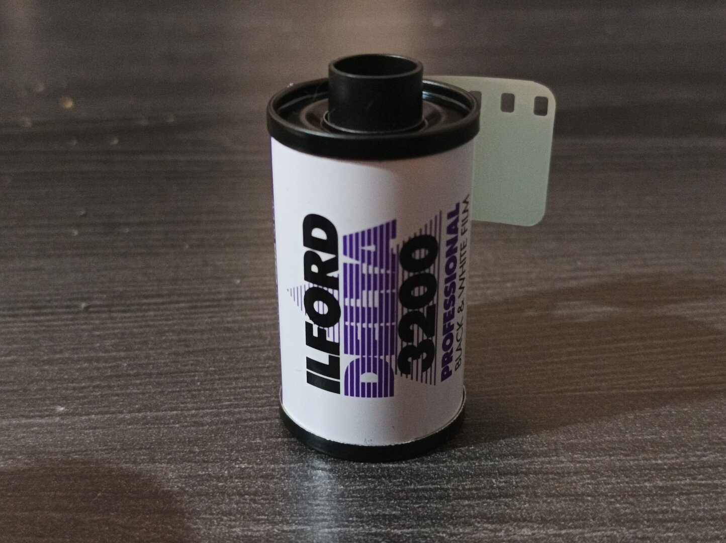 Picture of a white film roll, on a table, with the text "Ilford Delta 3200 Professional Black and White Film" written on it.