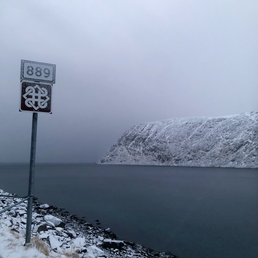 Et veiskilt med tallene 889 langs en fjord, i et vinterlandskap.