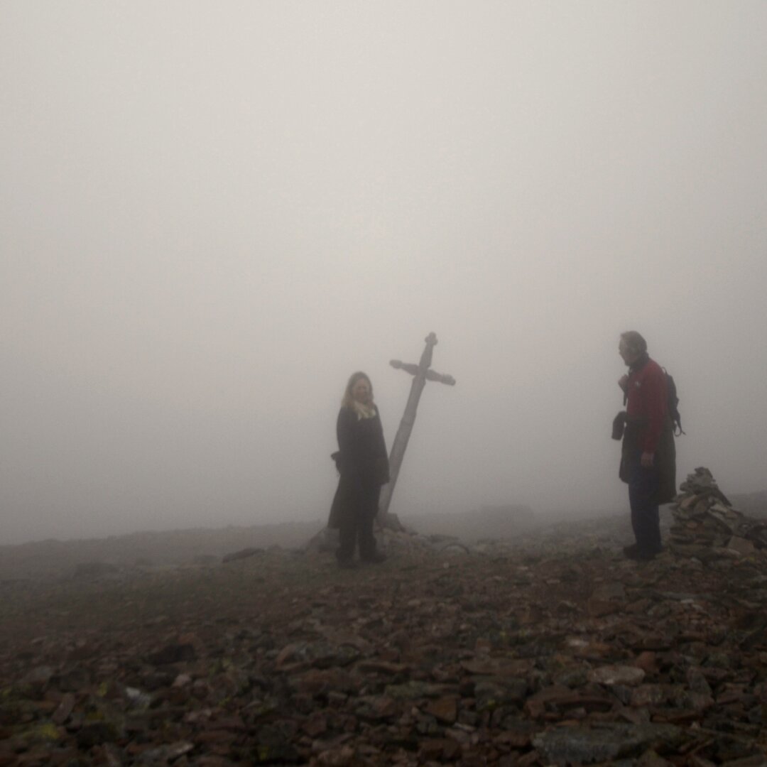 Tykk tåke, to mennesker og et skilt som ser ut som et kors.