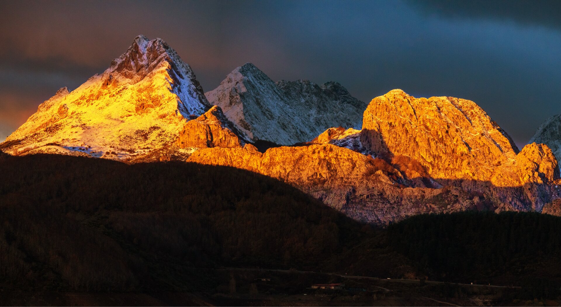 𝗣𝗶𝗰𝘁𝘂𝗿𝗲 𝗗𝗲𝘀𝗰𝗿𝗶𝗽𝘁𝗶𝗼𝗻 (𝗘𝗻𝗴): Panoramic view of the Riaño mountains at dawn: illuminated with warm tones, the Gilbo peak stands out on the left, the Cueto Cabrón massif on the right, and in the background, still in shadow, the peak Peña las Pintas. In the foreground, various beech forests extend, still in darkness, contrasting with the snow on the rocky cliffs. 𝗗𝗲𝘀𝗰𝗿𝗶𝗽𝗰𝗶𝗼́𝗻 (𝗘𝘀𝗽): Panorámica de montaña de Riaño al amanecer: iluminados con tonos cálidos destacan, a la izquierda el Pico Gilbo, a la derecha el macizo del Cueto Cabrón, y al fondo, aún en penumbra, la Peña la Pintas. En primer plano se extienden diversos hayedos aún en la oscuridad contrastando con las nieves de los farallones rocosos.