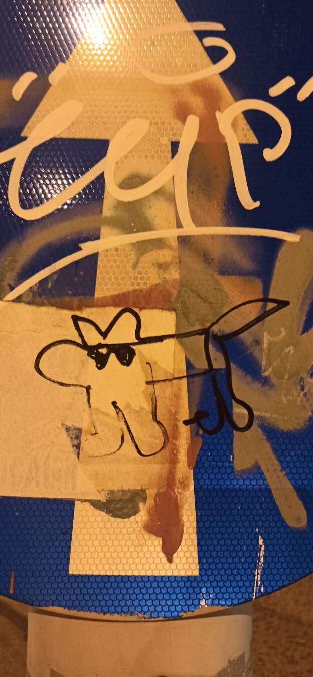 A photograph of a traffic table and the graffiti on it. Graffiti is a unskilledly drawn a dog which wears sunglasses.