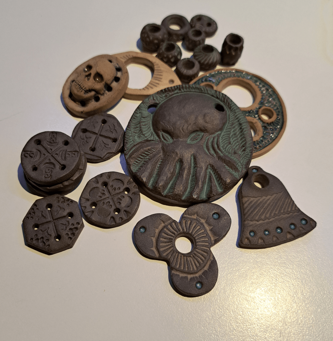 Clay pendants, pearls and buttons laying on a table like a pile of old treasure.