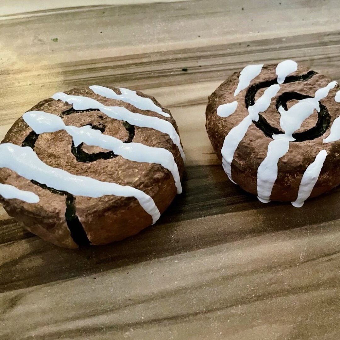 Props made of EVA foam and Cospaint, in the shape of freshly baked cinnamon buns. They are painted in different shades of brown, with some white latex Cospaint drizzled on to to imitate icing.