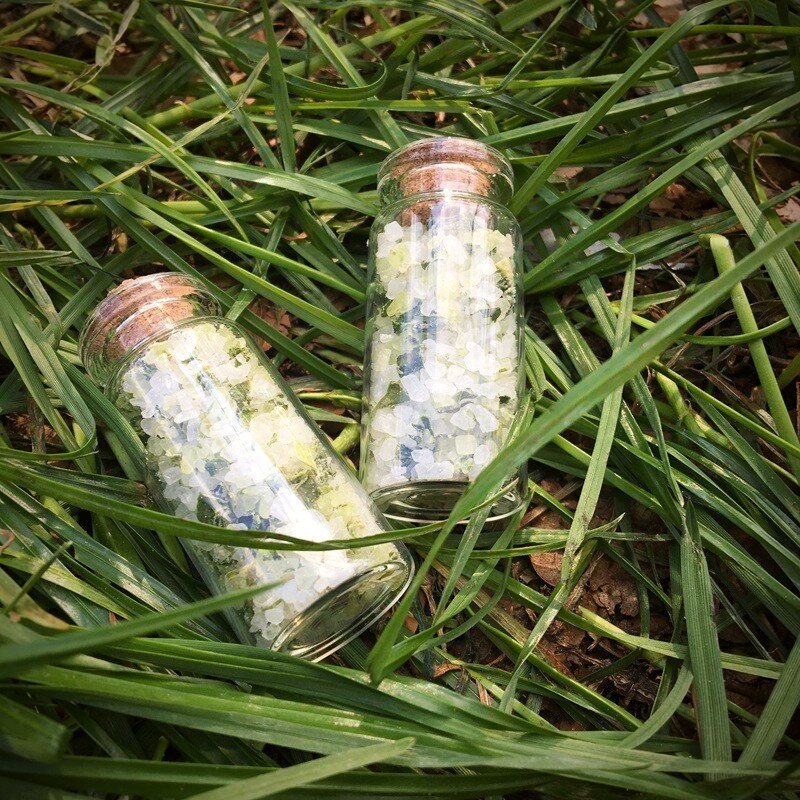 Two small corked bottles with greenisch Forest Salt, a mixture of sea salt with wild garlic, young spruce and pine tips. Brought to you by Fern Fiddlesticks, travelling hobbit lass and peddler of peculiar things.