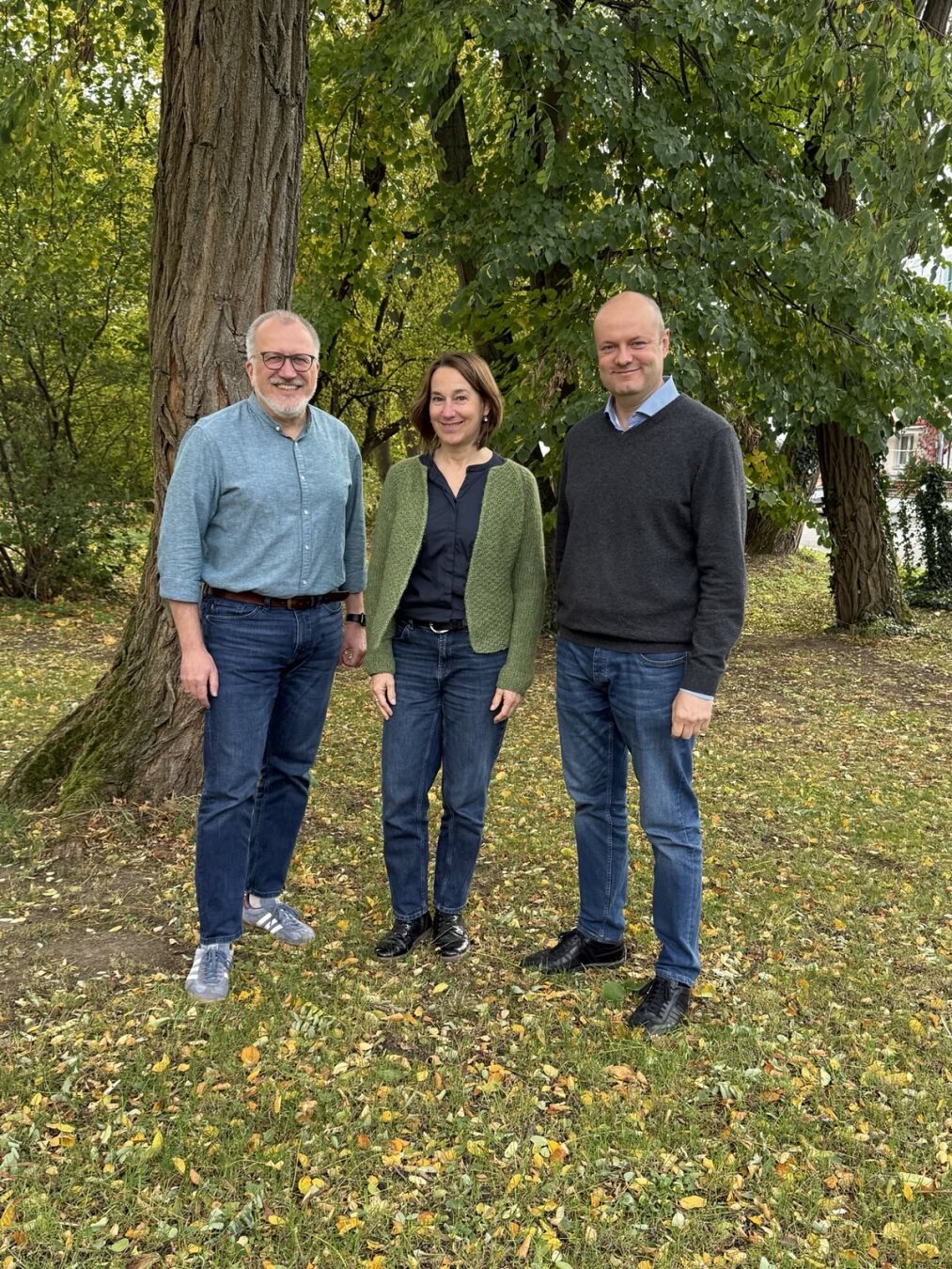 Jörg, Anne und Roman vor einem Baum im Herbstlaub stehend