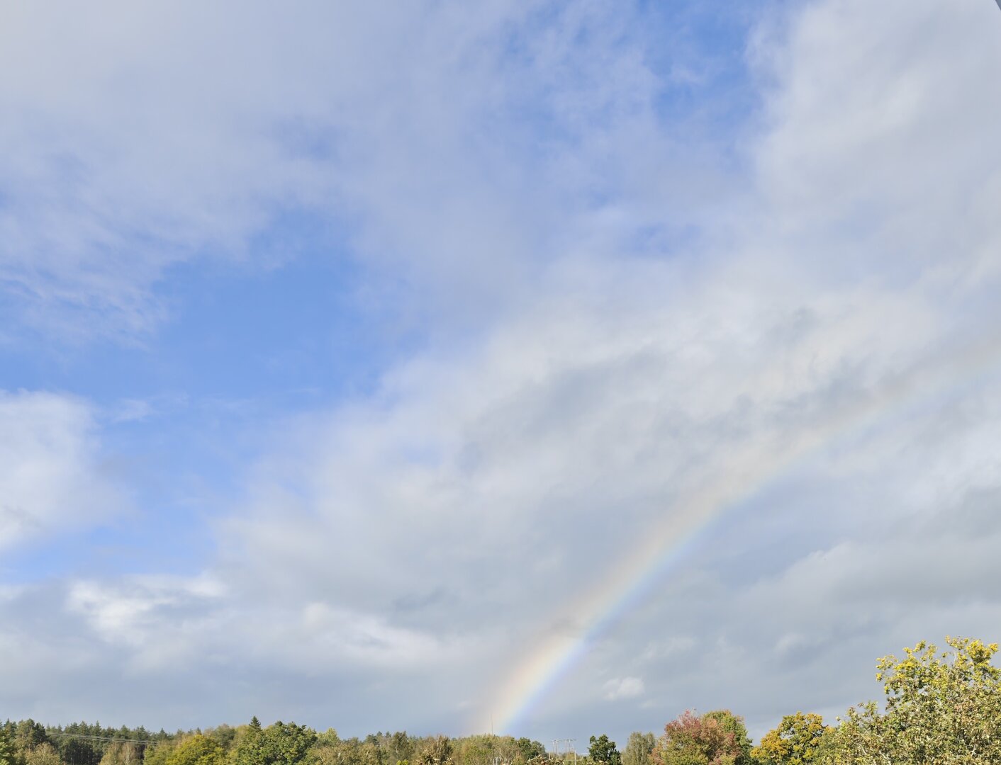 A rainbow over a blue, cloudy sky.