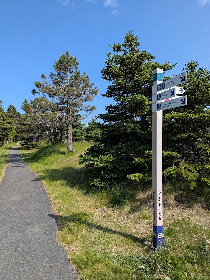 Trail marker sign next to a paved path