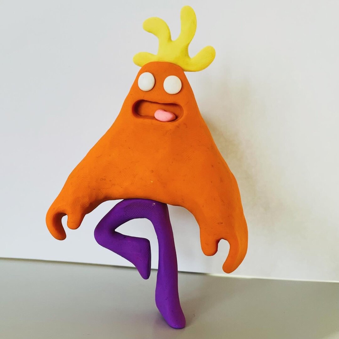 An orange clay character is a pose