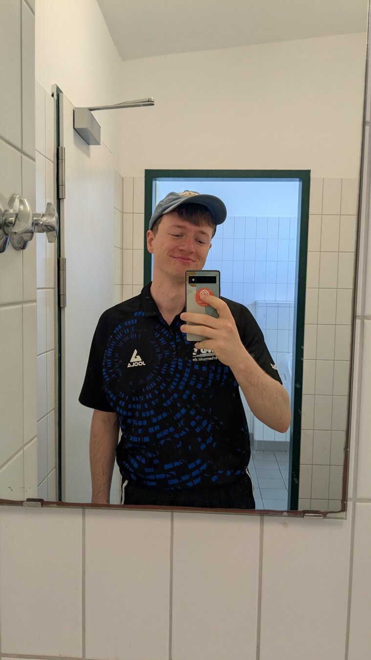 Ein Mann der sich im öffentlichen Bad im Spiegel fotografiert.