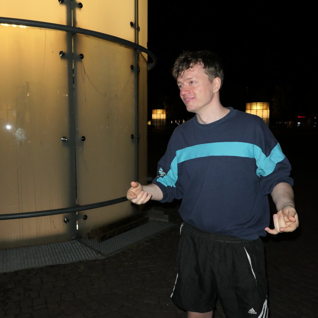 Nachtszene mit Blitzlicht, ein Typ steht und lächelt.