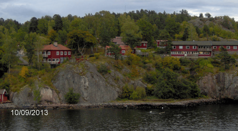 Red homes of varying sizes on cliffs of a forested island