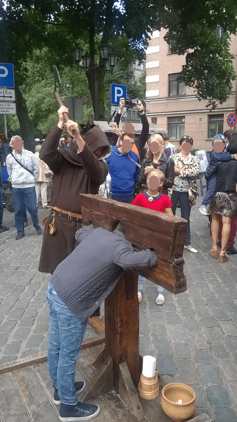 A young boy is in the stocks, the axe raised high