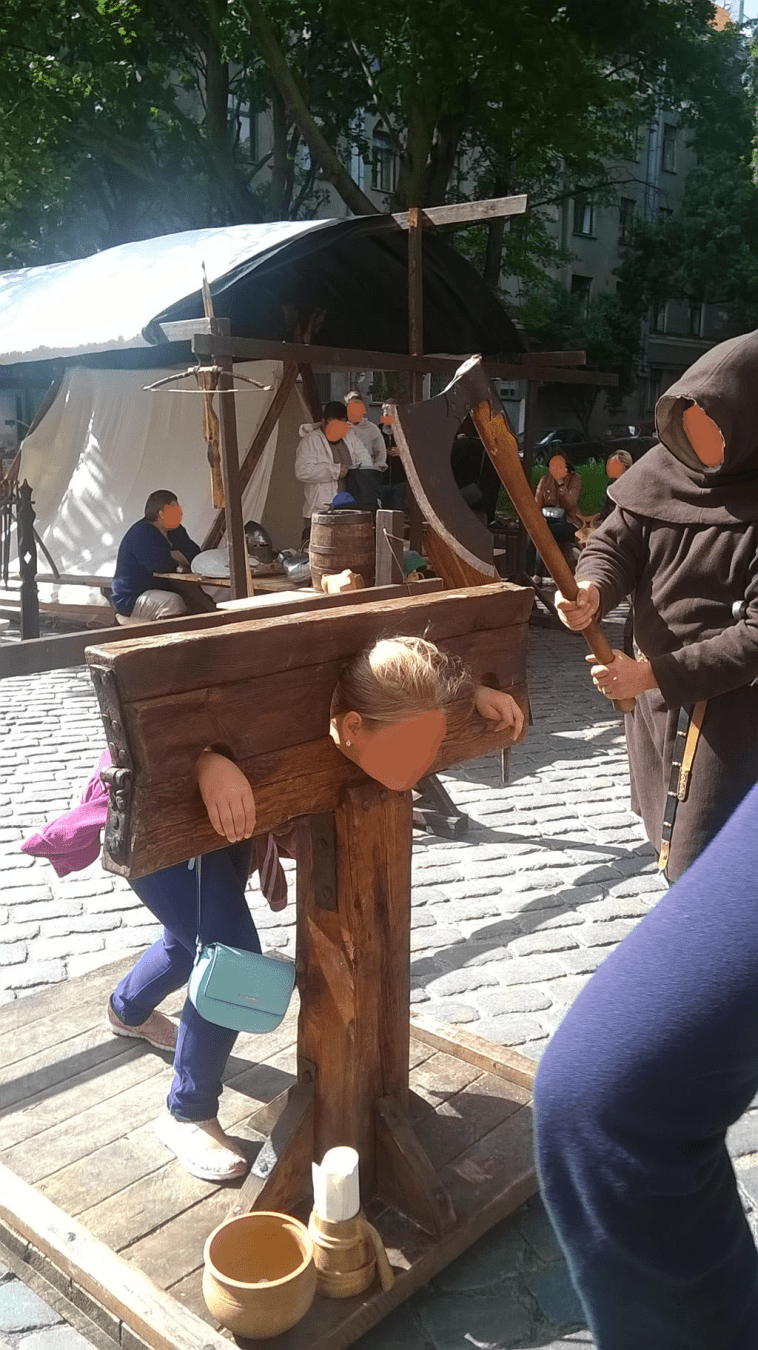 A young girl is in the stocks, the Executioner readying for the strike