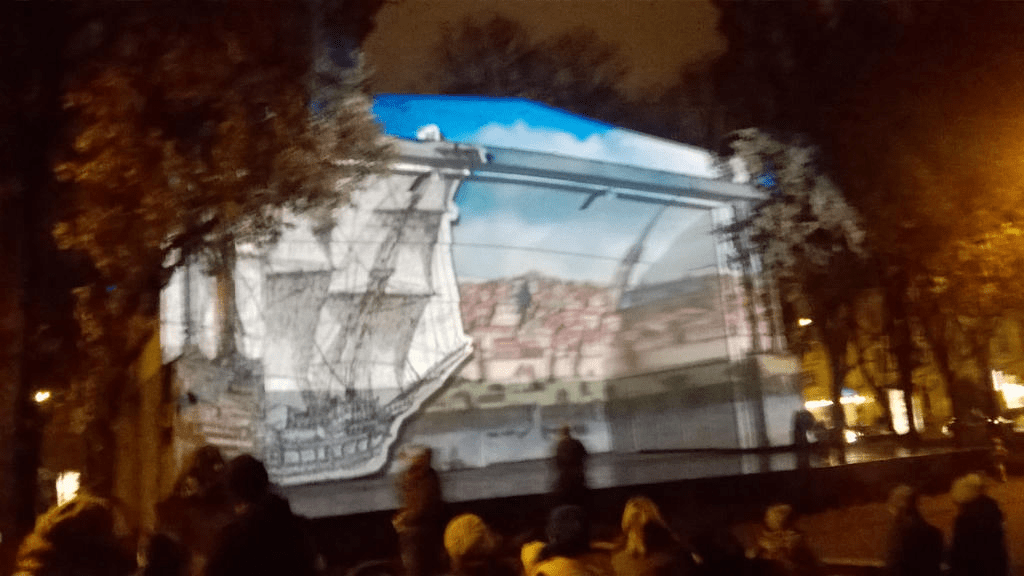 A cutout of a ship sailing across the painting of old Riga