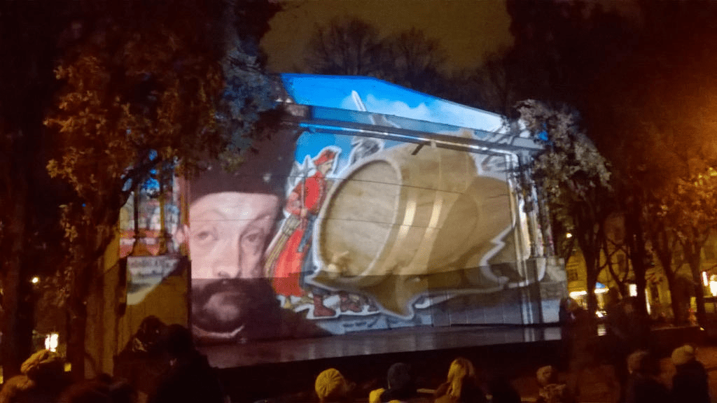 The man in red and black got closer to the viewer, with soldiers and barrels of alcohol joining him