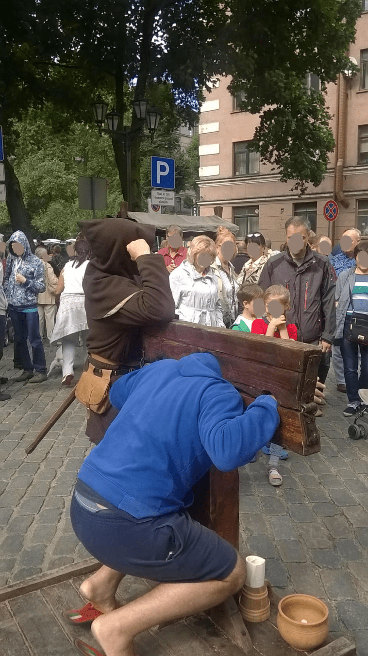 Except, the Executioner decides to take a break, put his axe down and is now leaning against the stocks, with the tall man still crouching in it
