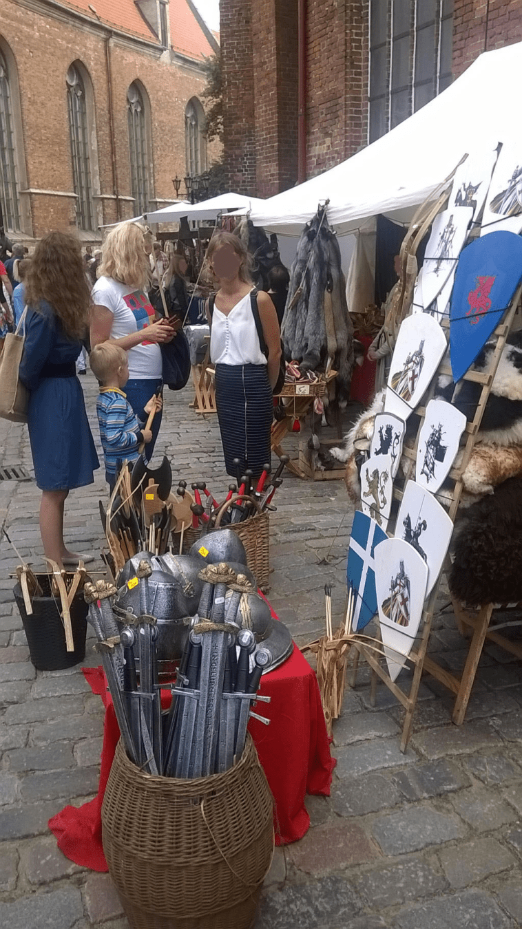 Stalls by St. Peters Church in Old Riga, wih toy weapons and shields and clothes, fitting a medieval fair