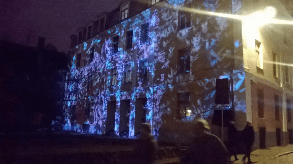 A house with its front bright with a light show of blue forms flashing across the bilding