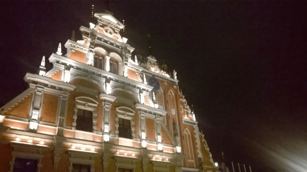 The House of Blackheads, its front lit up, against the dark sky