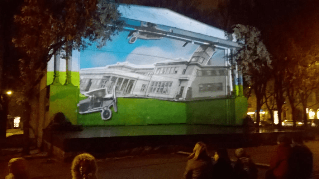 Cutouts of old airport buildings/ATC tower and old planes, with bright green grass and bright blue skies