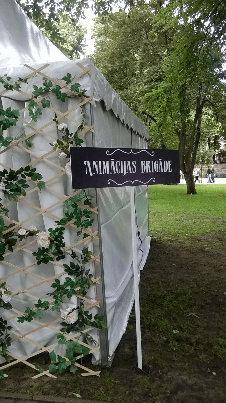 A sign by the tent in Latvian that says Animation Brigade
