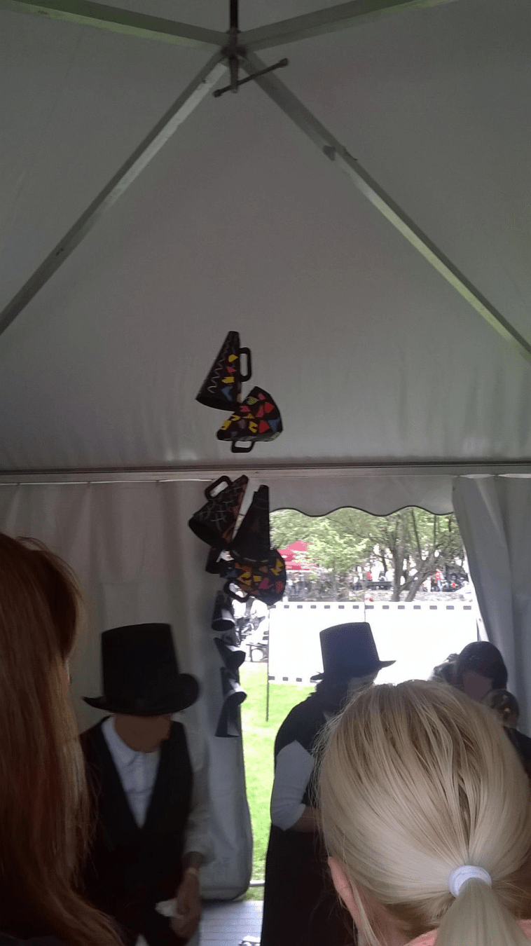 Focus on the ceiling of the tent, with paper megaphones attched on a strong, with people around the tent